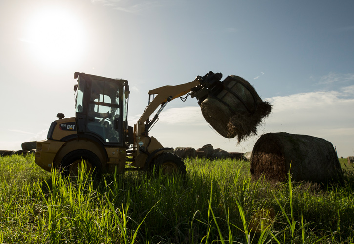 Piece of Cat equipment at work moving a bail of hay